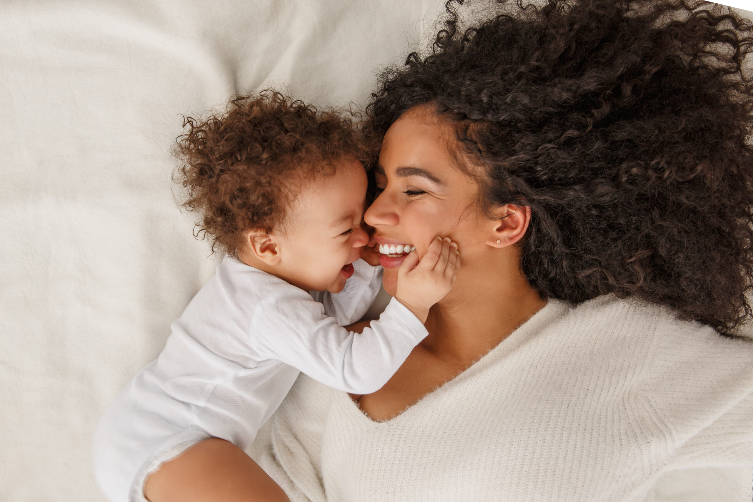 Mother and baby smiling and laughing together in bed