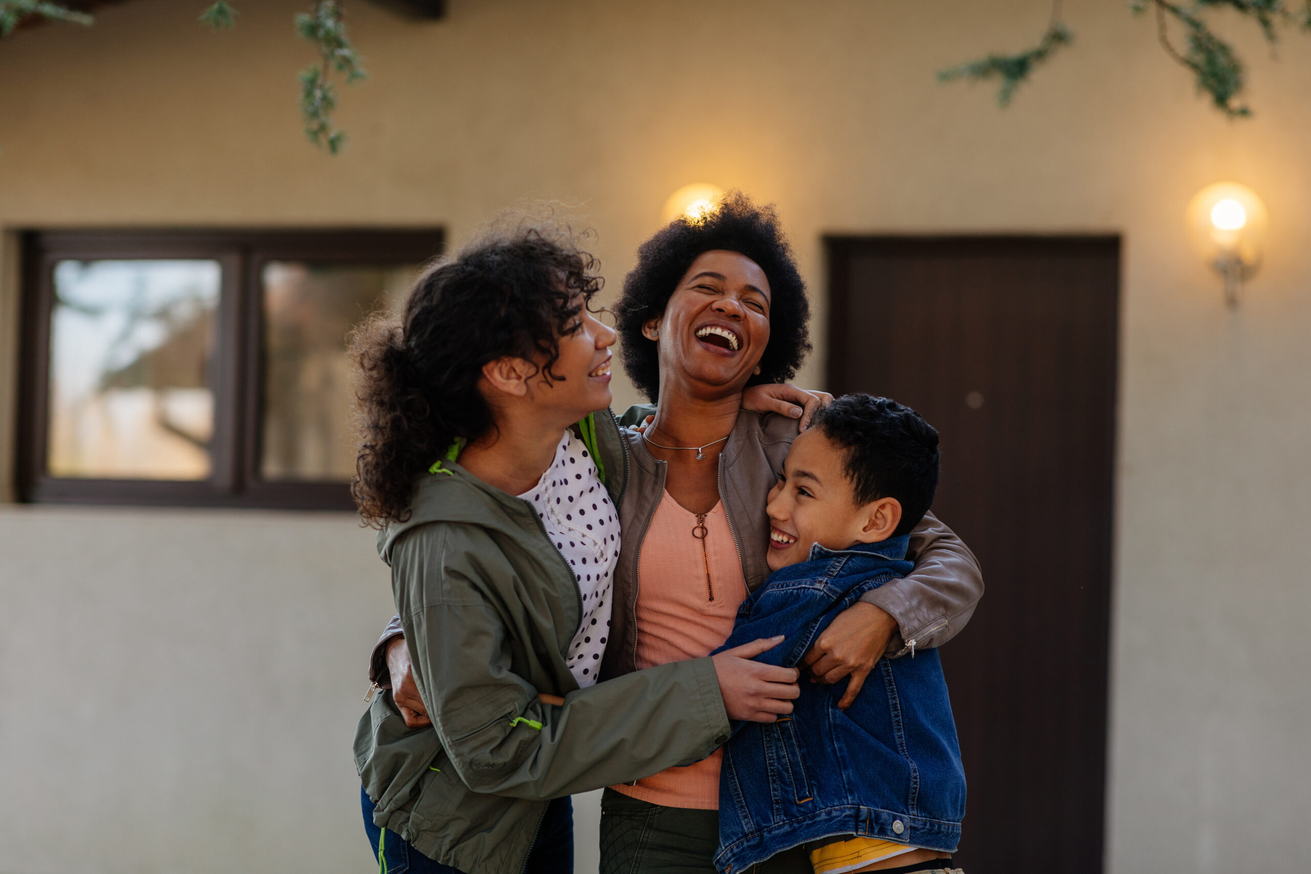 Mother hugging her children outdoors.