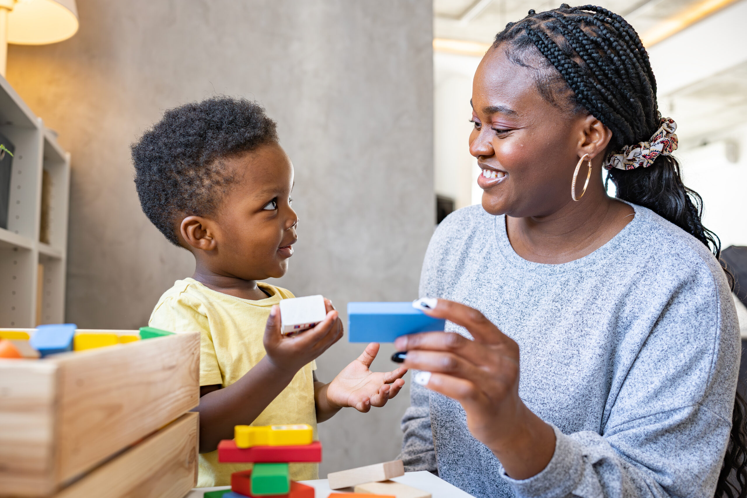 Preschool teacher and toddler playing with blocks